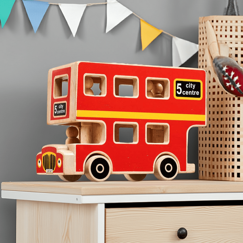 Wooden toy bus with '5 city centre' sign on a shelf with decorative flags in the background