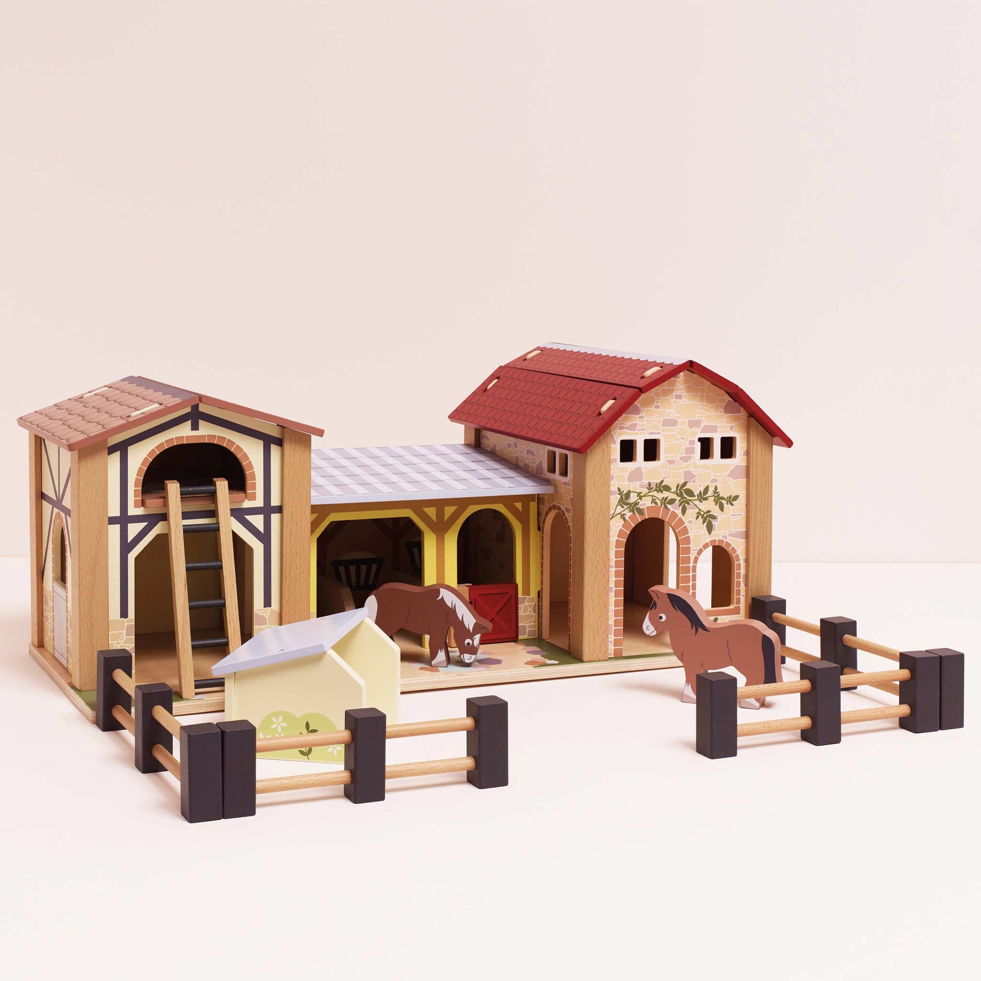 Toy horse stable set with two horses inside on a beige background
