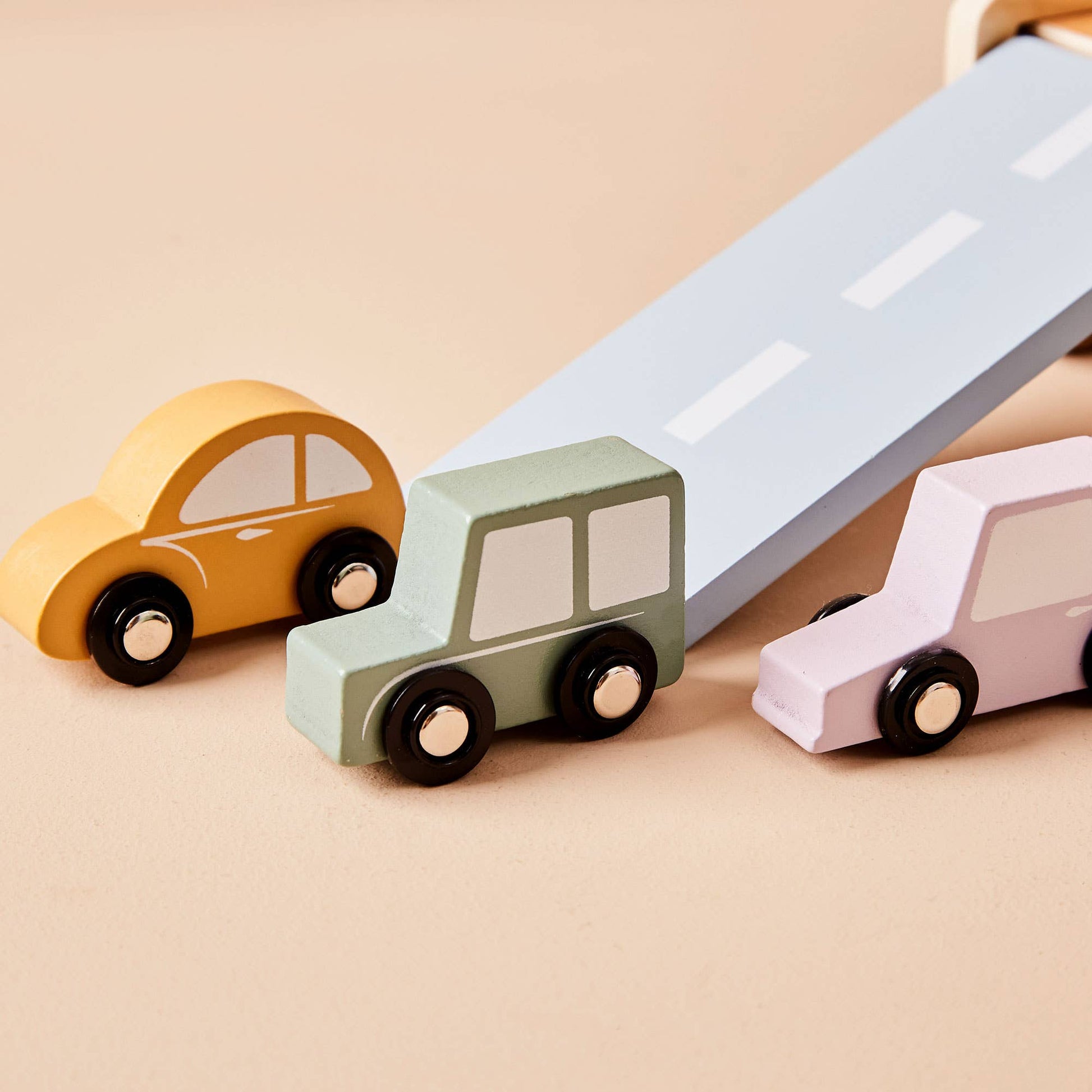 Three toy cars on a road with a beige background