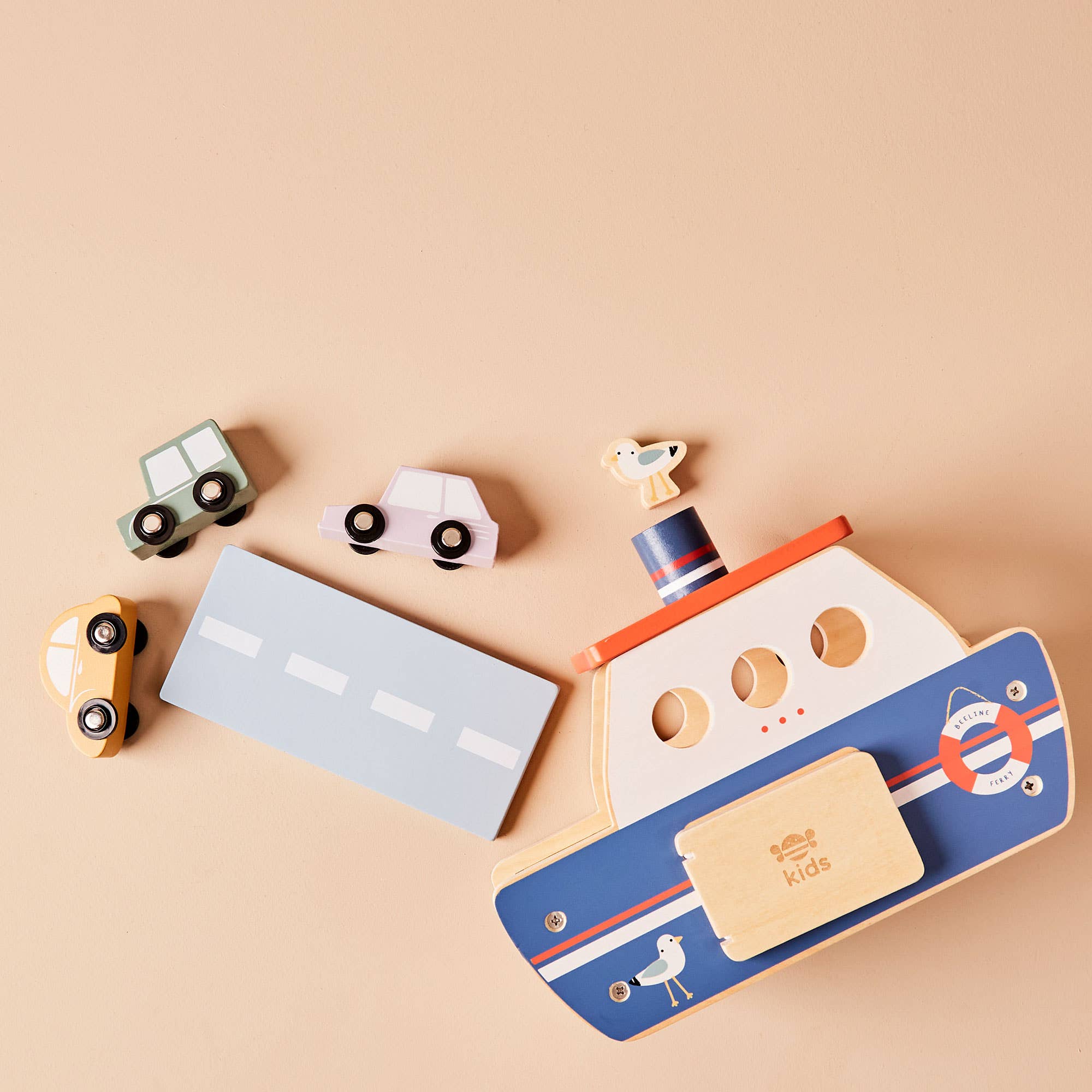 Set of wooden toys including cars and a boat on a beige background