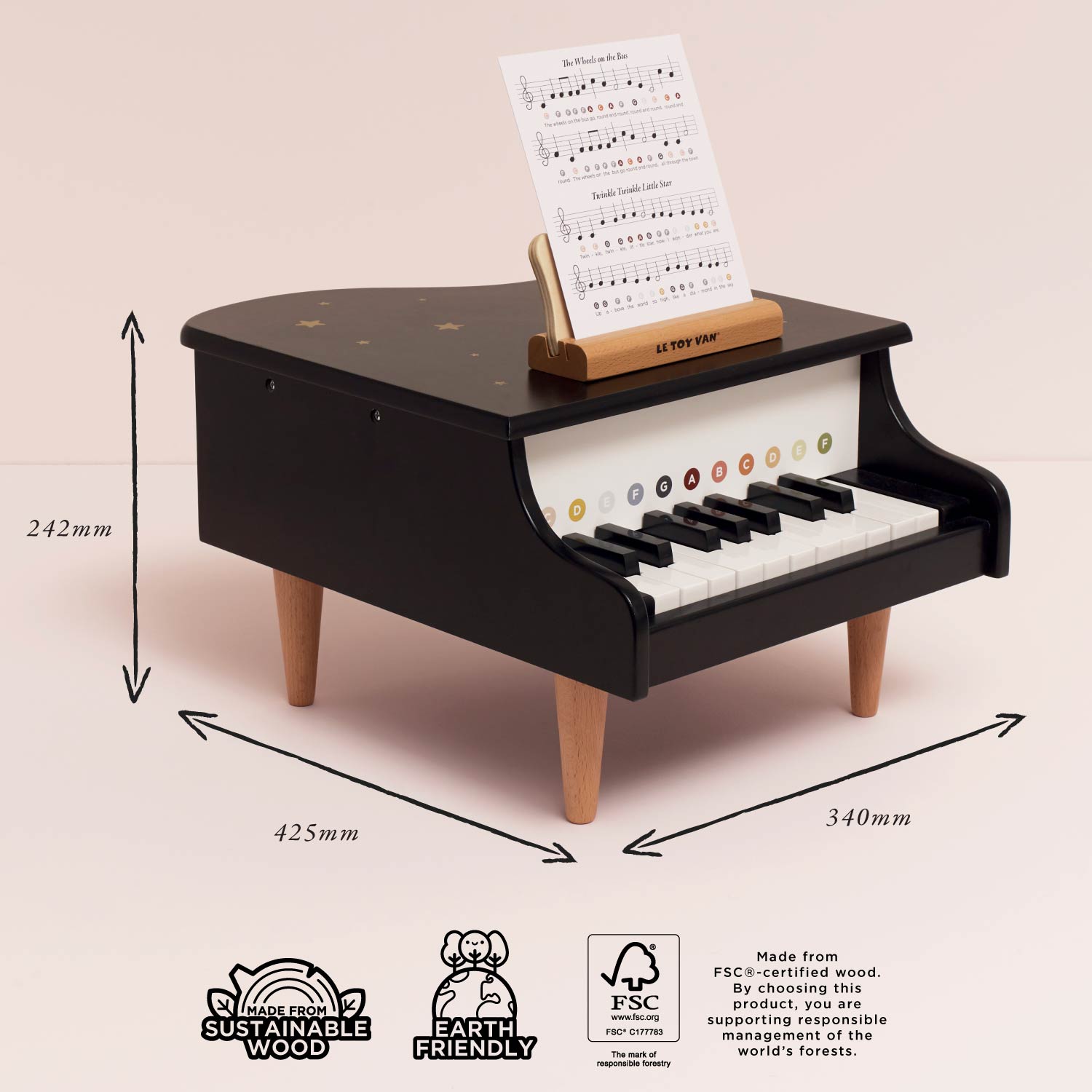 Black toy piano with dimensions and sustainability labels on a beige background