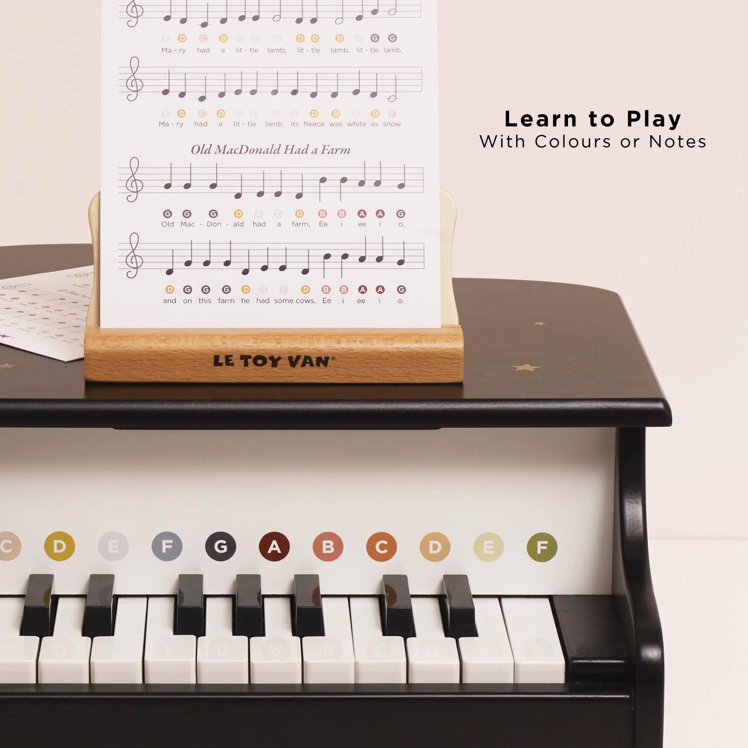 Le Toy Van piano with music sheet stand and educational music sheet on a light pink background