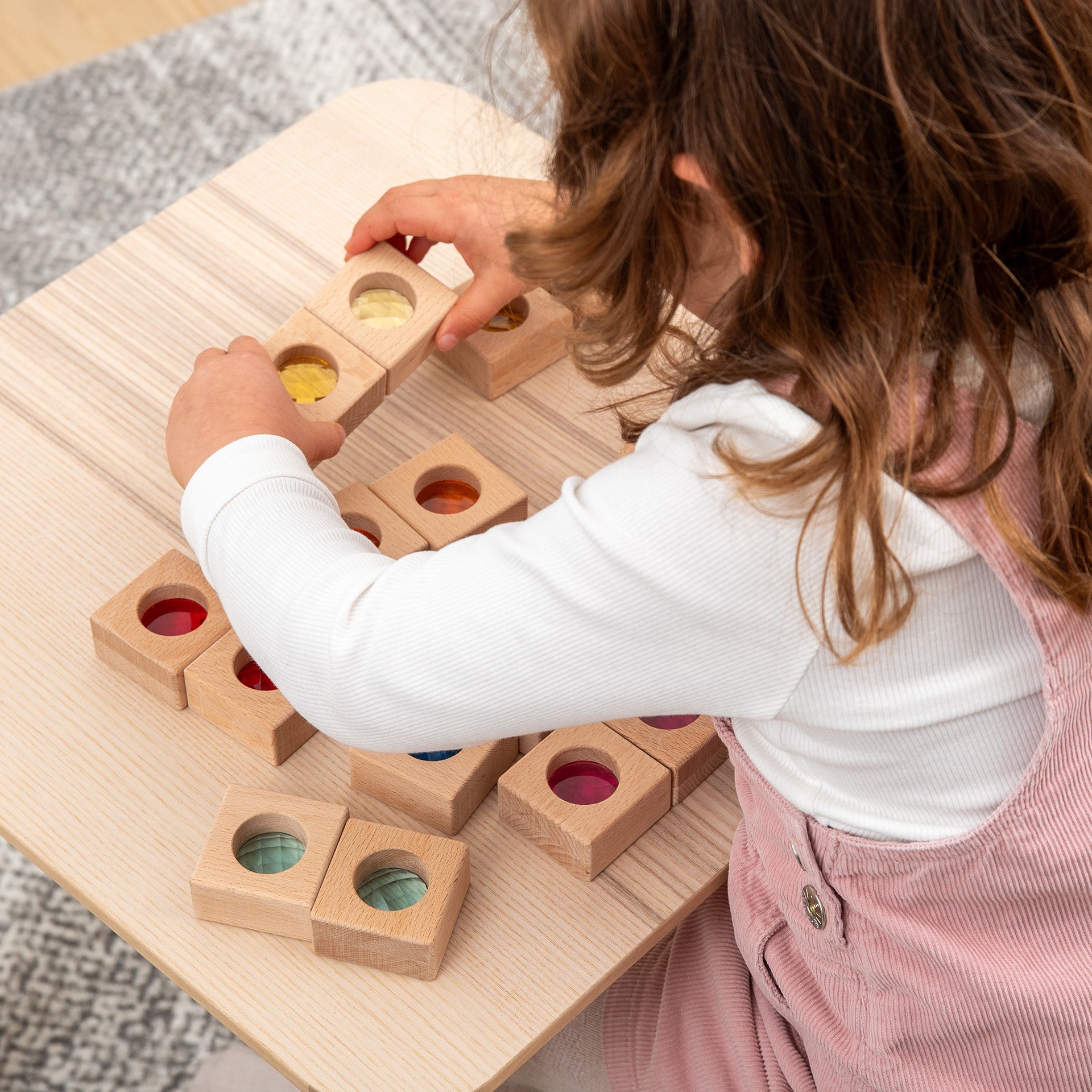 Child playing with wooden shape sorting toy on a wooden table