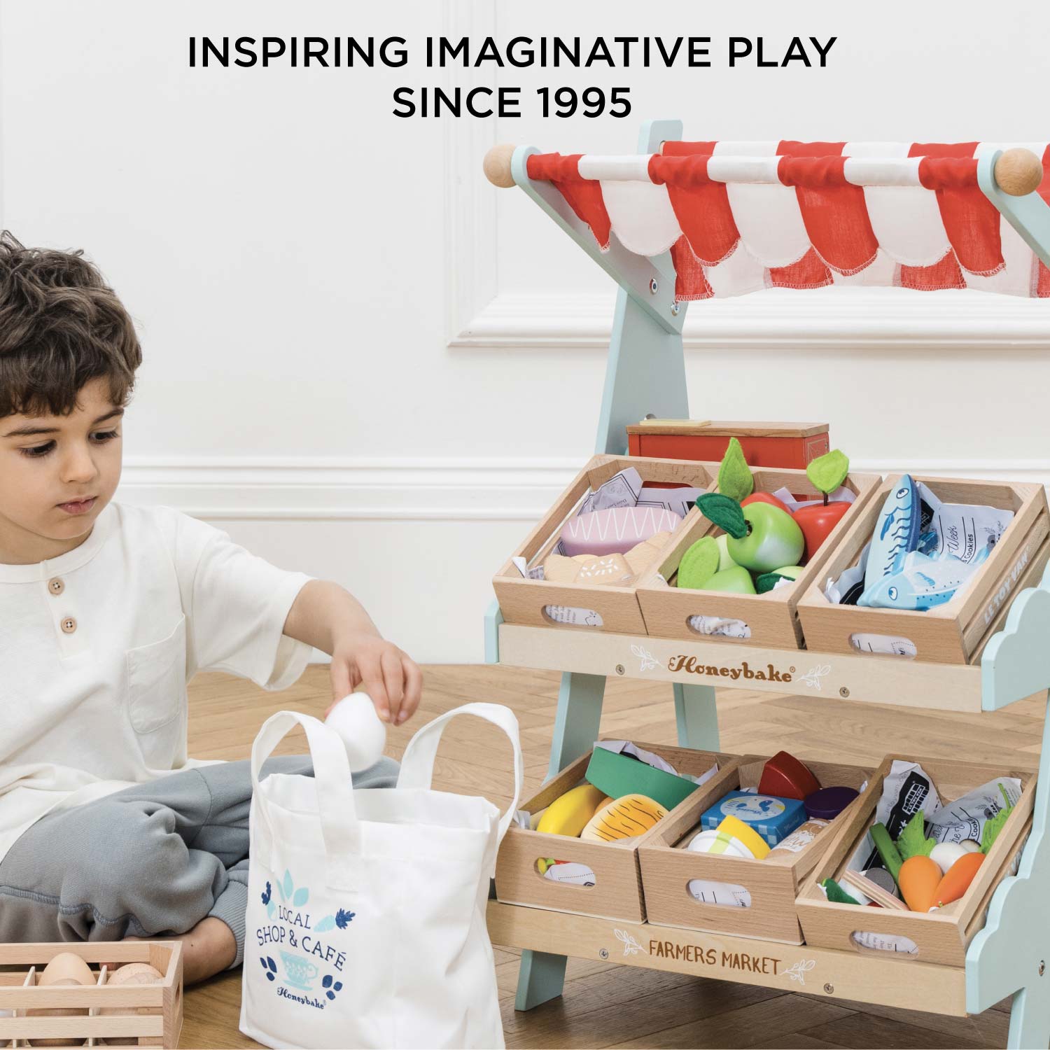 Child playing with a toy market set up, inspired by Honeybake brand since 1995.