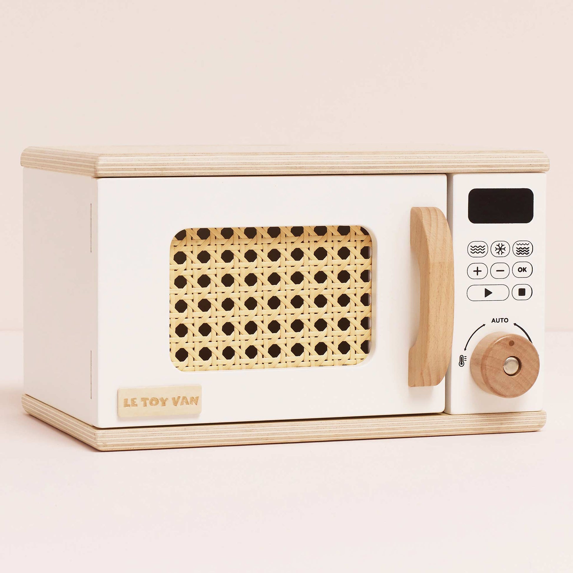 Toy microwave oven with wooden design on a light pink background