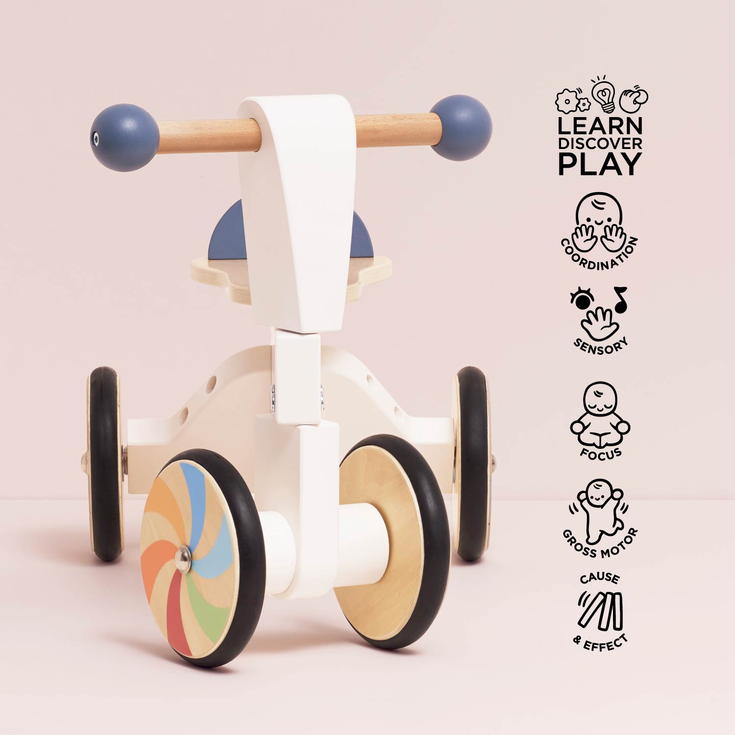 Children's wooden balance bike with colorful wheel design on a light pink background