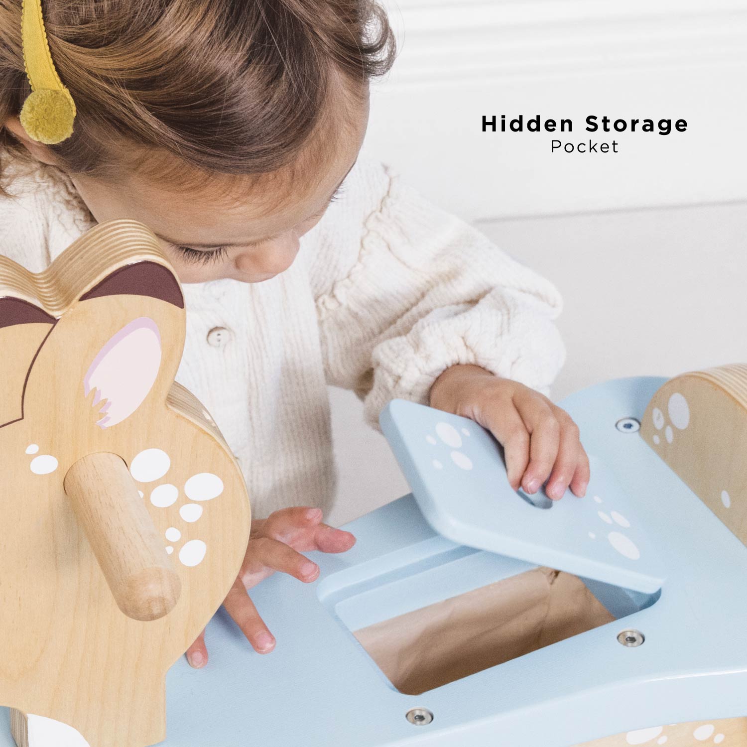 Child playing with a wooden toy, highlighting a hidden storage pocket feature.
