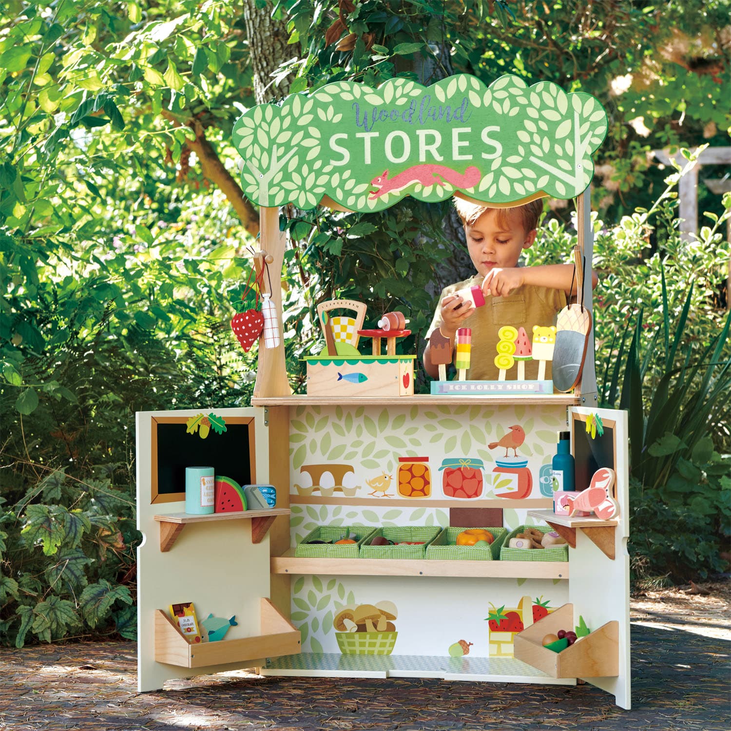 Child playing at a toy store set outdoors with greenery in the background