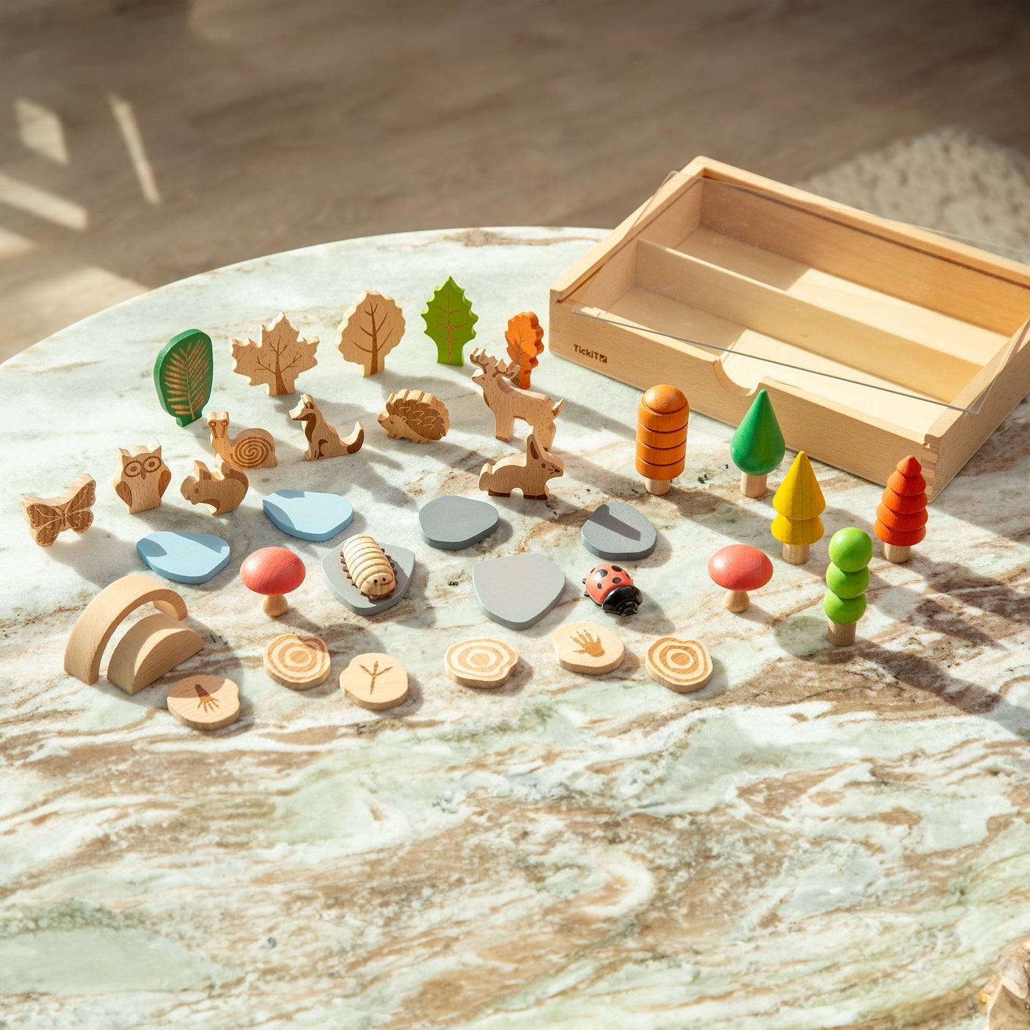 Set of wooden forest-themed toys on a marble surface with a wooden box.
