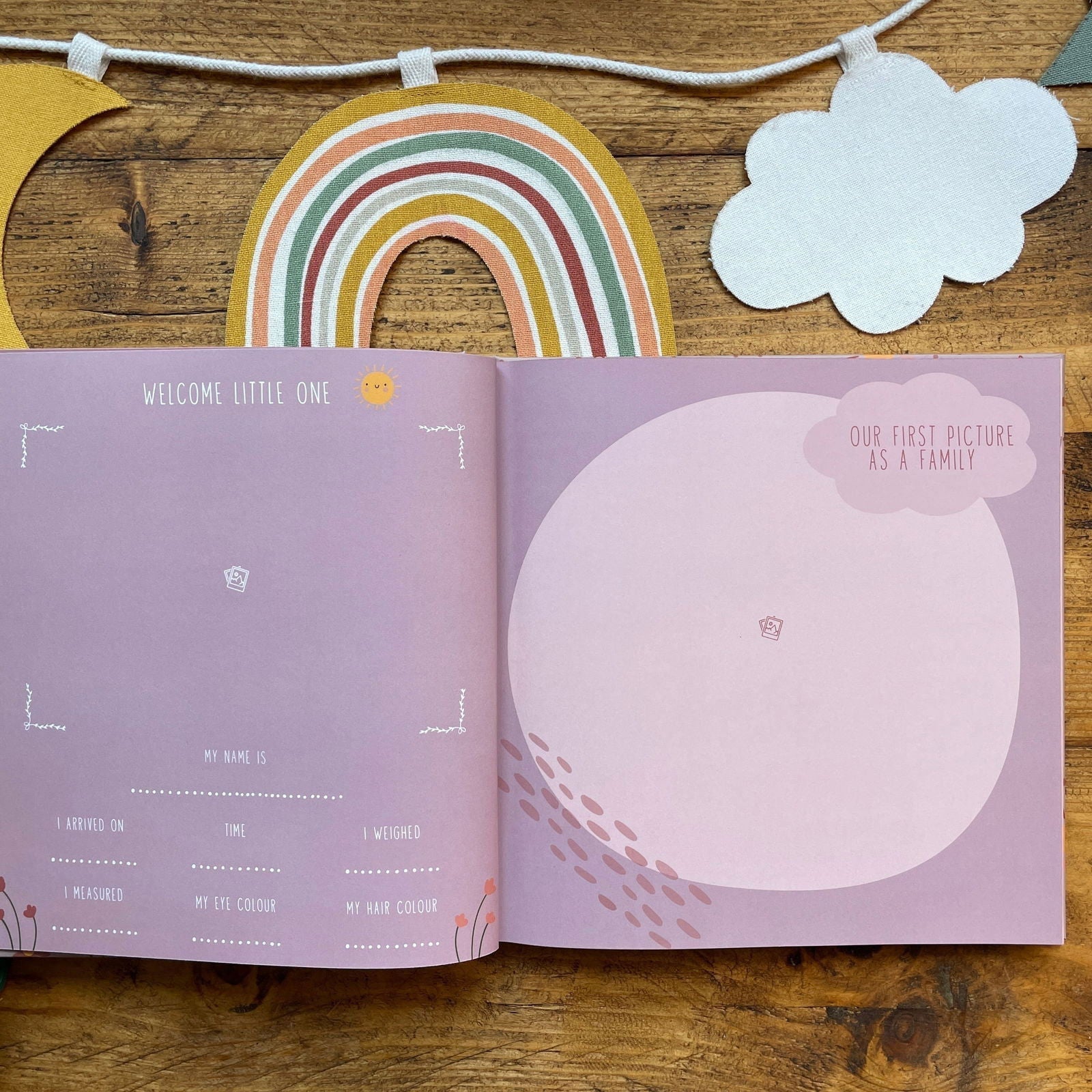 Open book with baby milestone tracker on a wooden surface with decorative elements.