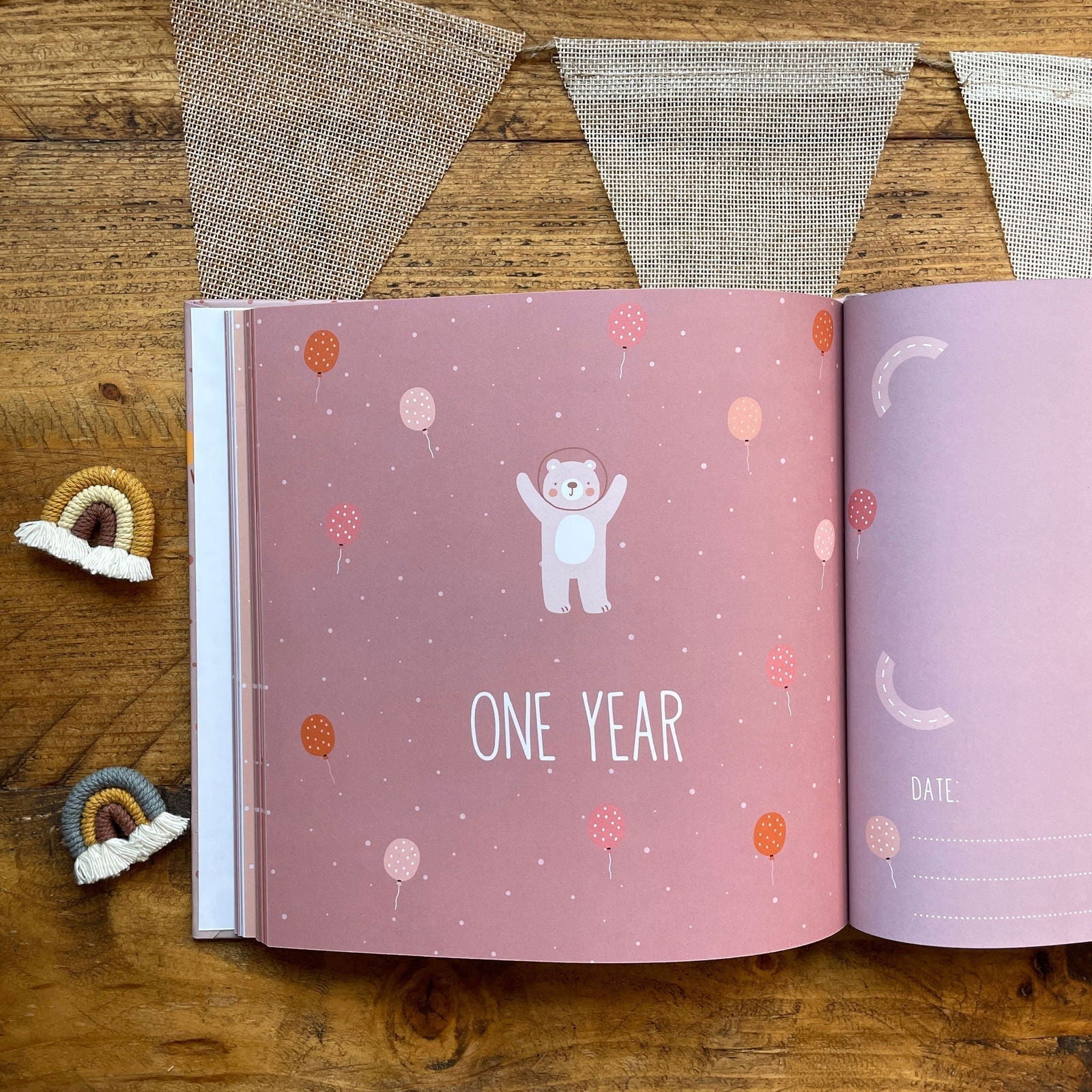 Open book with 'ONE YEAR' and bear illustration on a wooden surface with decorative elements.